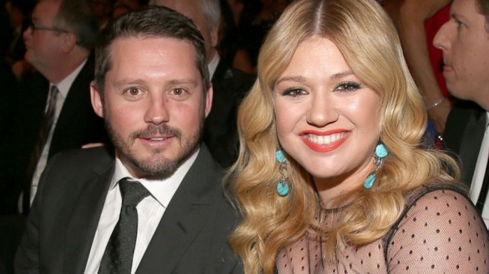 Kelly Clarkson with her canary diamond ring from her fiance Brandon Blackstock. The ring is surrounded by a halo and its band is inlaid with diamond.