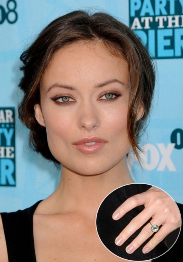 Olivia Wilde with her emerald-halo and round cut engagement ring that comes with a yellow gold setting.