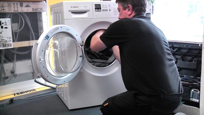 Top 10 Washing Machine Parts That Need Repair in Canada 18 technician repairing washing machine Top 10 Washing Machine Parts That Need Repair in Canada - 18