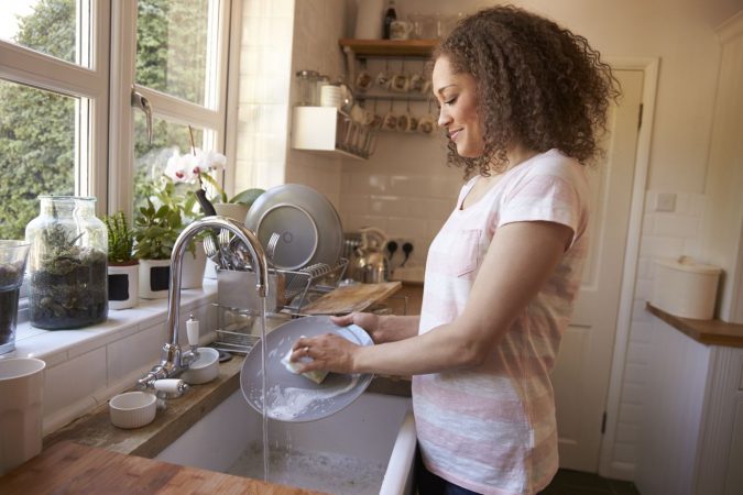 woman standing at kitchen garbage disposal 10 Tips to Buy Best Garbage Disposals for Different Waste Types - 3