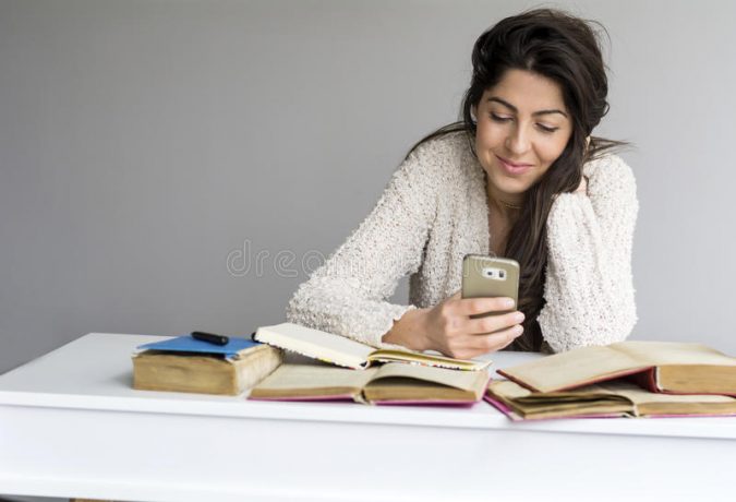 woman studying exams phone hand female student sitting desk pile study books mobile 87386547 7 Ideas for Improving Your Productivity In College - 7