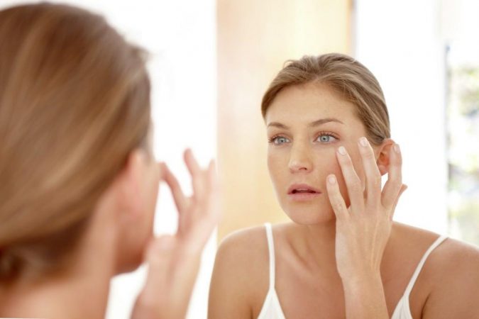 Easiest 7 Ways to Get Rid of Beauty Marks 6 woman looking at mirror Easiest 7 Ways to Get Rid of Beauty Marks - 6
