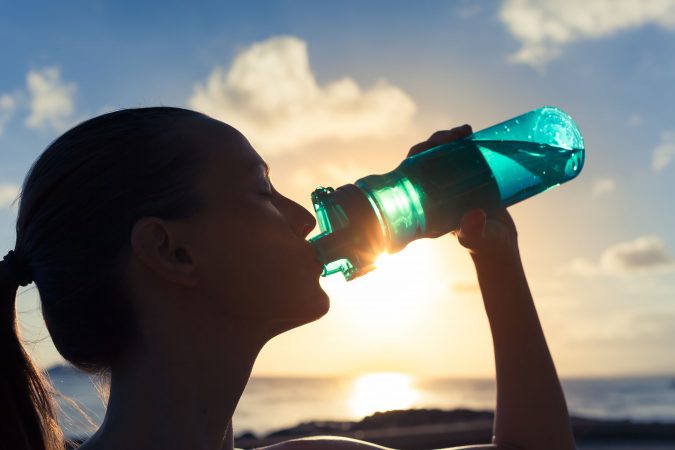 drinking from reusable water bottle 5 Travel Tips to Help You Save (Or Gain) Money on Your Next Trip - 8