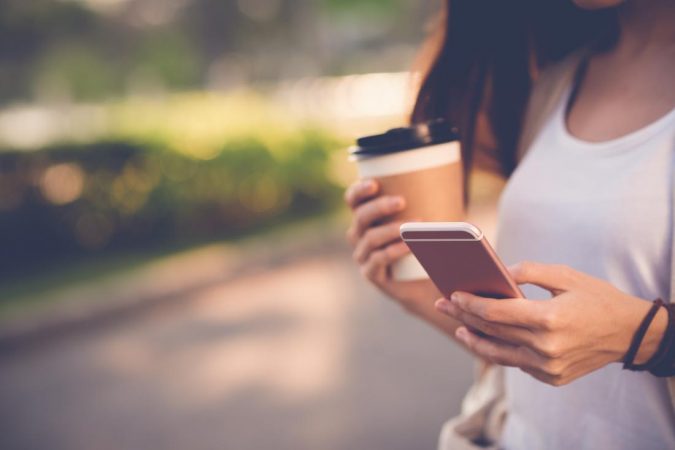 Top 5 Reasons to Use Cell Phone Tracker 8 woman holding coffee and mobile Top 5 Reasons to Use Cell Phone Tracker - 8