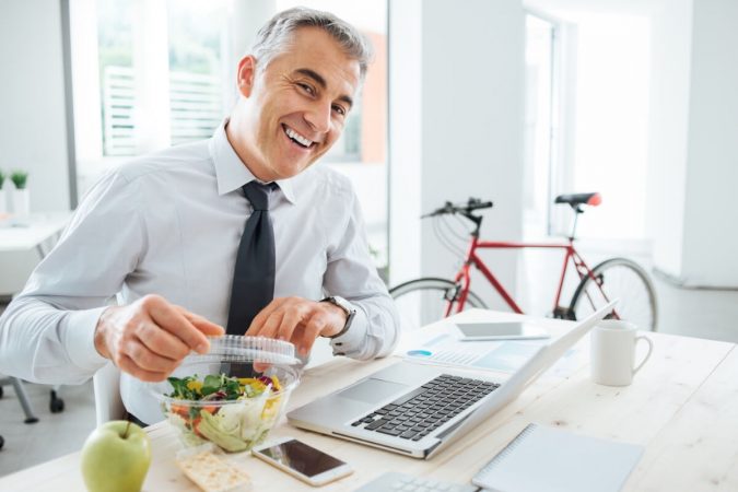 6 Ways to Stay Healthy on a Busy Schedule 12 healthy man eating lunch at work 6 Ways to Stay Healthy on a Busy Schedule - 12