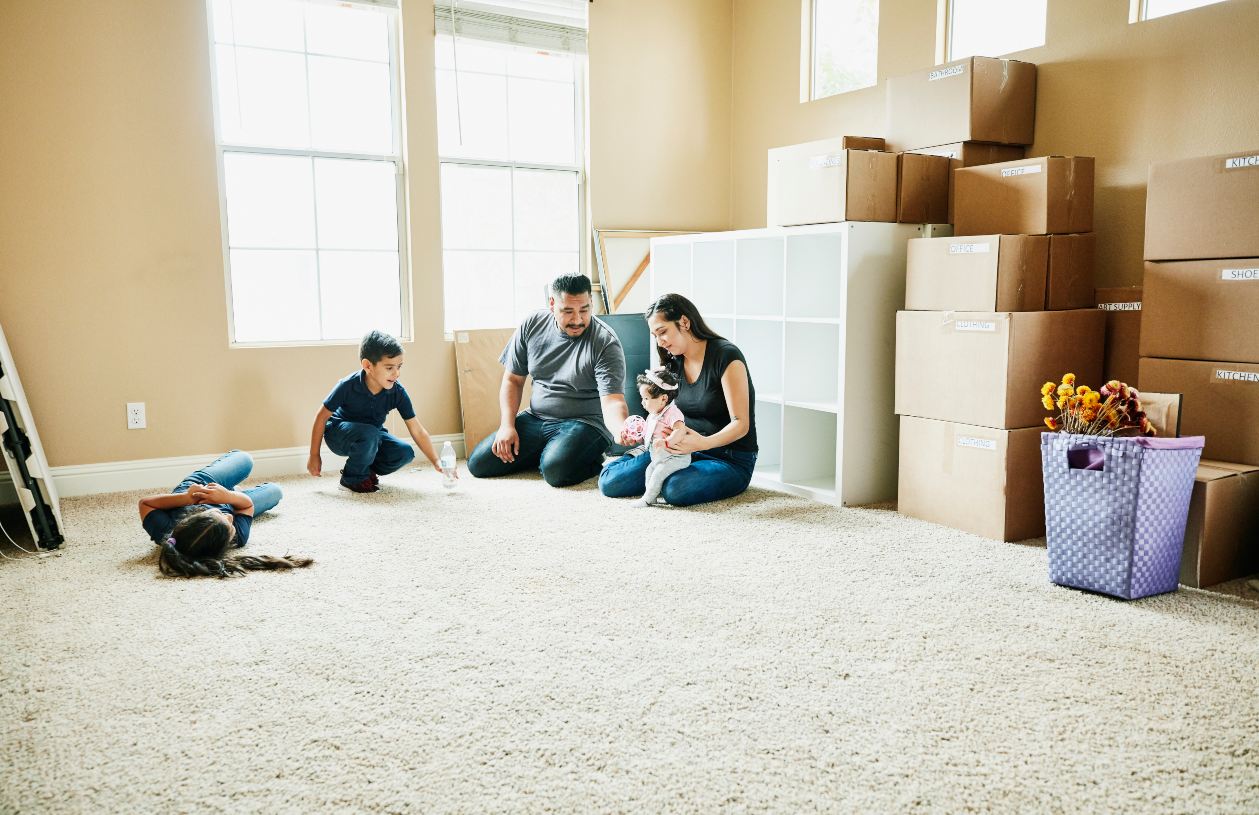 Family sitting on floor of living room of new home during move in day